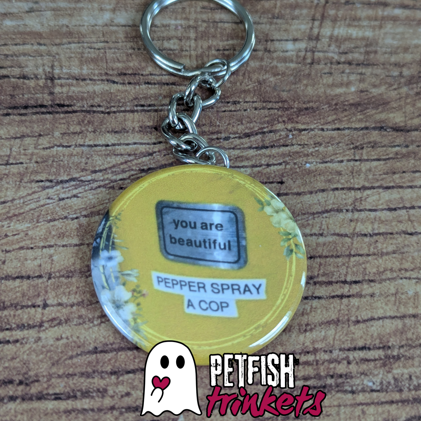 A 1.75in keychain that reads You Are Beautiful, Pepper Spray a Cop